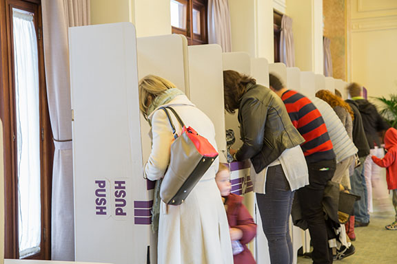 Voters marking their ballots in a row of polling booths