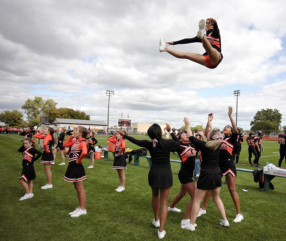 Cheerleaders lifting a teammate high into the air in a stunt