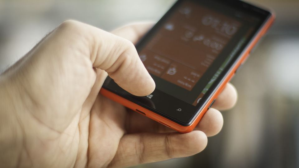 A hand holding a smartphone with apps on the screen