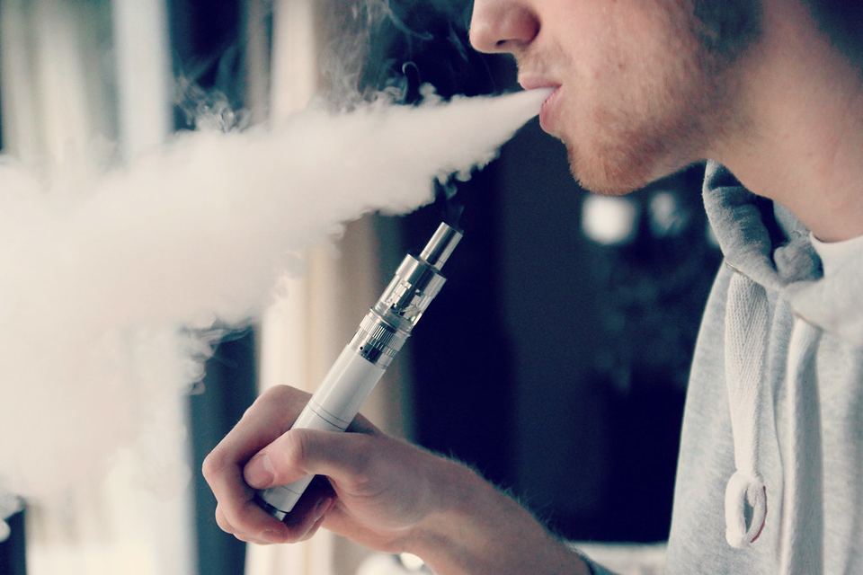 A person exhaling a cloud of vapor from an e-cigarette